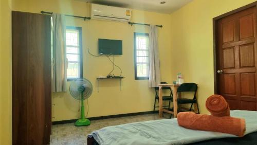 a bedroom with a bed and a desk with a fan at Floral House in Lamai