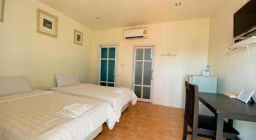 two beds in a room with a desk at Le Bar Tarry Hotel in Loei