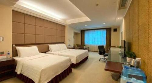 a hotel room with two beds and a desk at Changchun Zhuozhan Days Hotel in Changchun