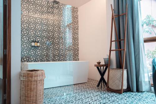 a bathroom with a tub and a tile floor at Casa de Arte Hotel Boutique in Oaxaca City