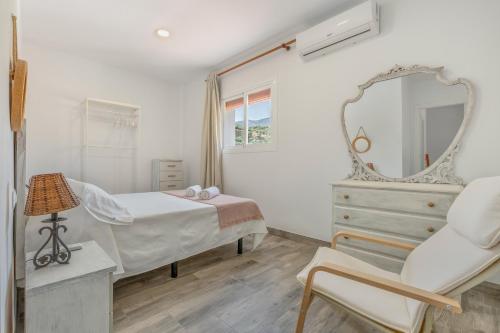 ein Schlafzimmer mit einem Bett, einem Spiegel und einem Stuhl in der Unterkunft Casa con Vistas a Sierra Nevada in Saleres