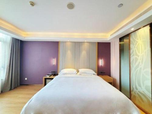 a large white bed in a room with purple walls at Lavande Hotel·Dongxing Port in Fangcheng