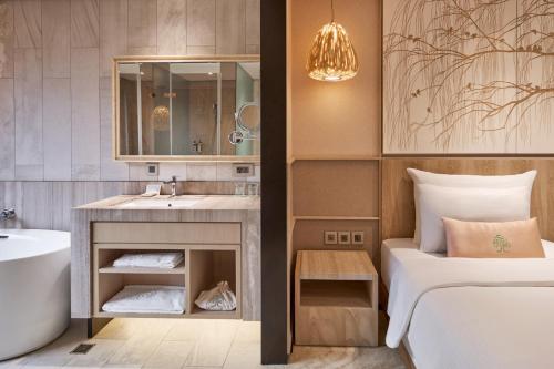 a bathroom with a bed and a sink and a tub at arTree hotel in Taipei