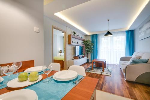 a dining room and living room with a table and chairs at River Boulevards Apartment in Kraków