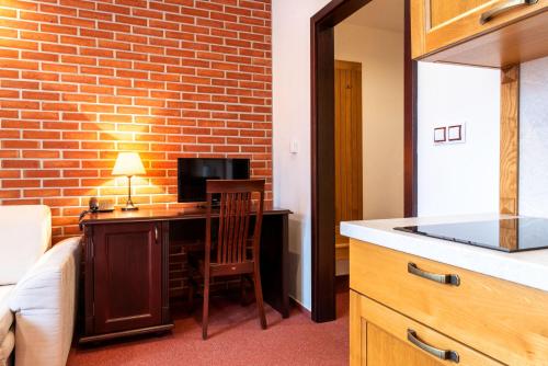 a room with a desk with a television and a brick wall at Hotel Purkmistr in Plzeň