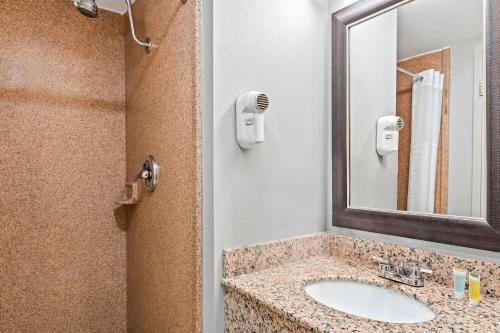 a bathroom with a sink and a mirror at Travelodge by Wyndham Bloomington in Bloomington