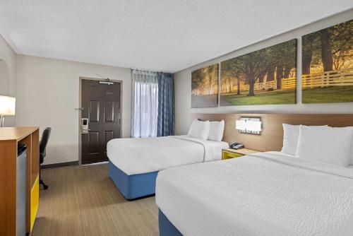 a hotel room with two beds and a desk at Days Inn by Wyndham Chattanooga/Hamilton Place in Chattanooga