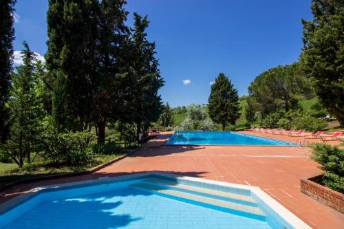 a large swimming pool with chairs and trees at Borgo Il Poggio Agriturismo in Montaione