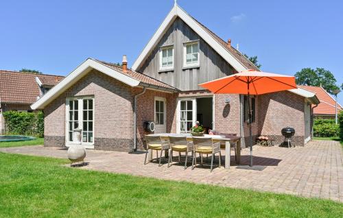 a house with a table with chairs and an umbrella at Buitengoed Het Lageveld - 52 in Hoge-Hexel