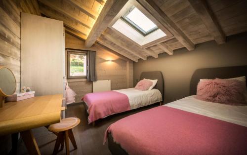 - une chambre avec 2 lits avec des draps roses et une lucarne dans l'établissement Résidence Hibou Blanc - Superbe chalet à l'atmosphère scandinave et à la situation idèale ! MAE-3881, à Montriond