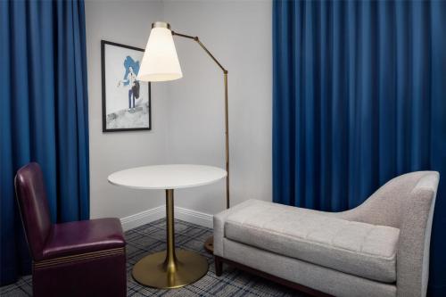 a living room with blue curtains and a table and a chair at The Skirvin Hilton Oklahoma City in Oklahoma City