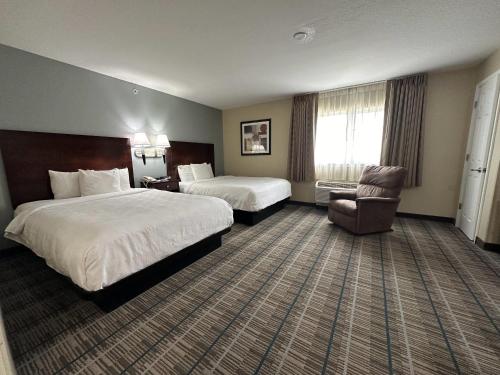 une chambre d'hôtel avec deux lits et une chaise dans l'établissement MainStay Suites Coralville - Iowa City, à Coralville