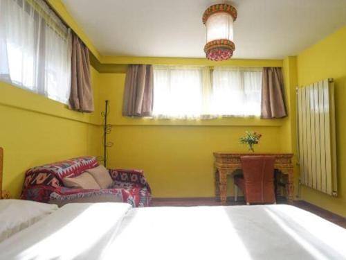 a bedroom with a bed and a chair and windows at Tashitakge Hotel in Lhasa