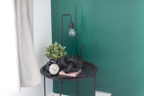 a table with a clock and a plant and a lamp at CastleView Haven - Contractors welcome -Strood Rochester sleeps 12 in Strood