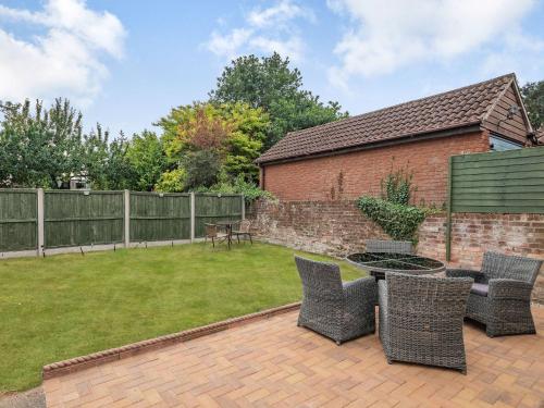 a patio with chairs and a table in a yard at Manager's Cottage in Loddon