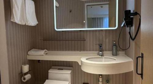 a bathroom with a sink and a mirror and a toilet at Magnotel Shanghai Maglev Station in Shanghai