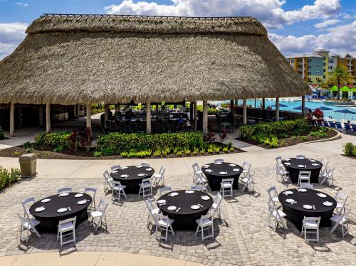 an outdoor patio with tables and chairs and a thatch roof at Embassy Suites By Hilton Orlando Sunset Walk in Kissimmee