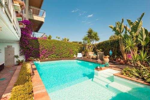 a swimming pool in front of a building with plants at Villa Cannizzaro in Catania