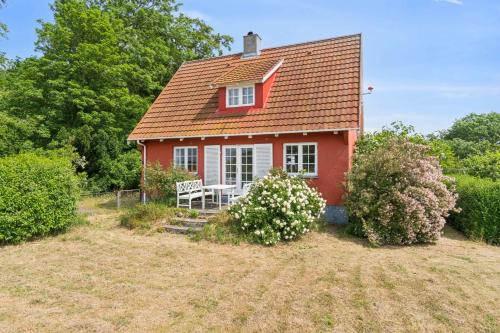 a small red house with a bench in a yard at Family Holiday Near Beach, Town And Nature in Svaneke