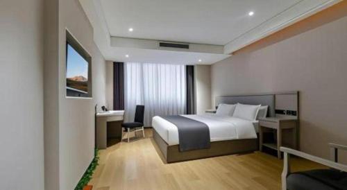 a hotel room with a bed and a desk and a window at GreenTree Inn Fuyang Yijing International North Business in Fuyang