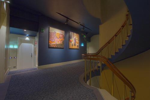 a hallway with a staircase and paintings on the wall at Hotel Touring in Ferrara