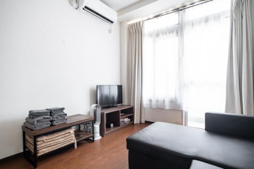 a living room with a couch and a television at 3ベッドルームとリビング 4部屋全て個室 混まない2つのシャワールームとトイレ 東新宿駅2分8名 in Tokyo