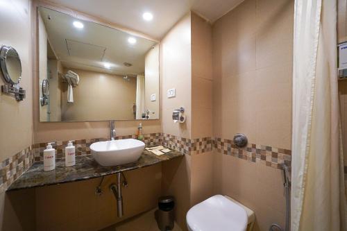 a bathroom with a sink and a toilet and a mirror at Open Hotel by Olive - The Infantry Hotel in Bangalore
