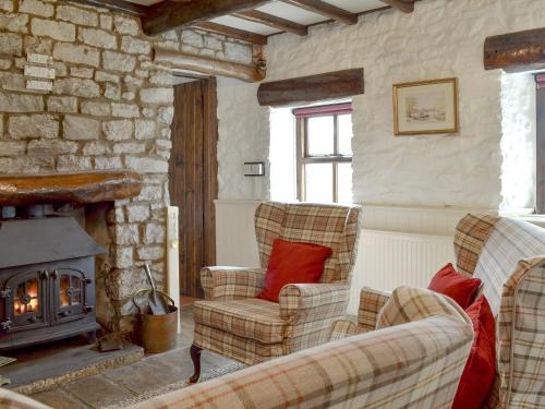 a living room with two chairs and a fireplace at Oxlow End Cottage in Peak Forest