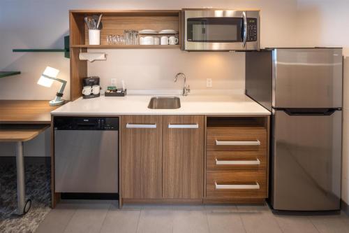 a small kitchen with a sink and a refrigerator at Home2 Suites By Hilton Kalispell, Mt in Kalispell
