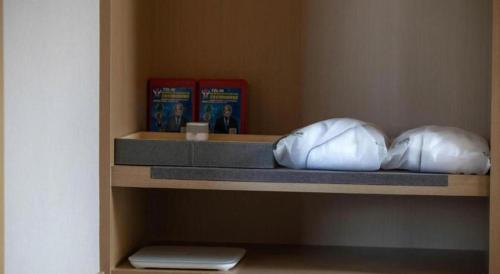 two pillows sitting on a shelf with books at Atour Hotel Weihai Shidao in Dongshan