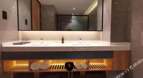 a bathroom with a sink and a mirror and towels at Xian Union Alliance Atravis Executive Hotel in Xi'an