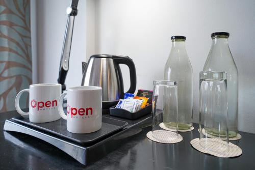 two coffee mugs and two glass bottles on a counter at Open Hotel by Olive - The Infantry Hotel in Bangalore