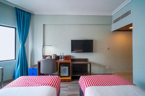 a hotel room with two beds and a television at Open Hotel by Olive - The Infantry Hotel in Bangalore