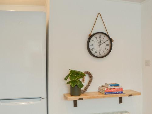 a clock on a wall next to a shelf with a plant at Crescent By The Sea in Newbiggin-by-the-Sea