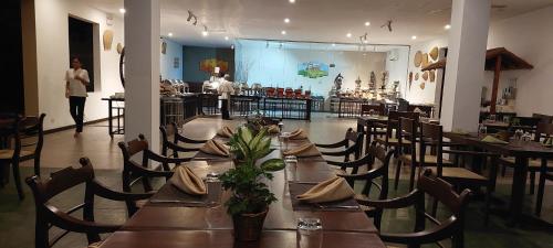 a restaurant with tables and chairs and a woman in the background at Kassapa Lions Rock in Sigiriya