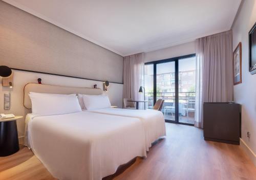 a bedroom with a large white bed and a balcony at Hotel Madrid Alameda Aeropuerto, Affiliated by Meliá in Madrid