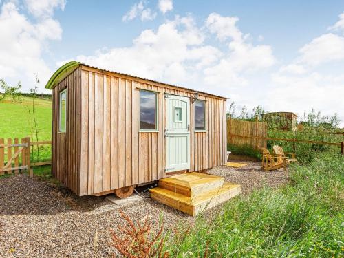 a small wooden cabin with a door and a porch at Woodside Hut 2 - Uk36106 in Auchterneed