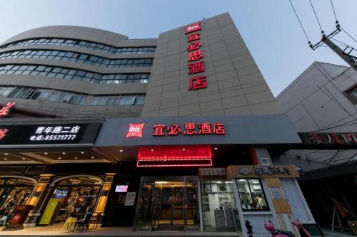 a tall building with red signs on it at Ibis Nantong Qingnian in Nantong