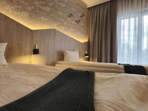 a hotel room with two beds and a window at Mikołajki Resort Hotel & Spa Jora Wielka in Mikołajki