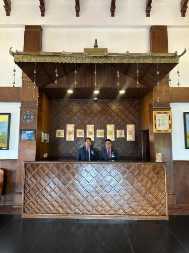 two men are standing behind the counter of a courtroom at Chandragiri Hills Resort Kathmandu-Luxury in the Clouds in Thānkot