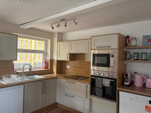 una cucina con mobili bianchi e un lavandino di Cosy little house on Great Orme a Llandudno