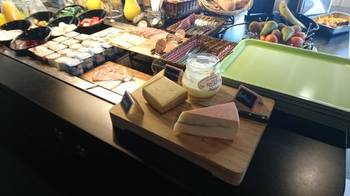 a table with a cutting board with different types of cheese at Hotel Campanile Besançon Nord Ecole Valentin in Besançon