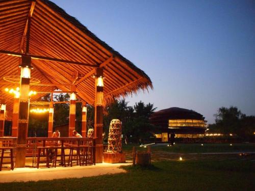 a pavilion with people sitting at a table at night at The Buffalo Amphawa in Samut Songkhram
