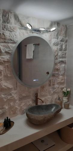 a bathroom with a stone sink and a mirror at Helios Boutique Maisonette in Astypalaia