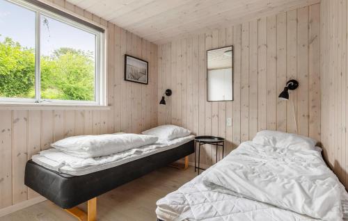 two beds in a room with wooden walls and a window at Nice Home In Vejby With Sauna in Vejby