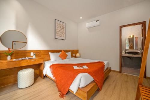 a bedroom with a bed with an orange blanket on it at Tropical Villa - Near My Khe Beach & City Center by The Key in Da Nang