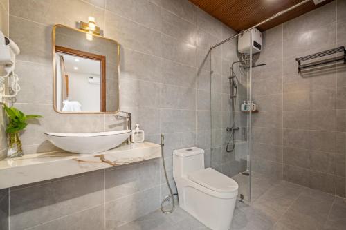 a bathroom with a sink and a toilet and a mirror at Tropical Villa - Near My Khe Beach & City Center by The Key in Da Nang