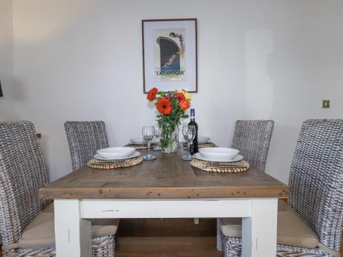 a dining room table with two chairs and a vase of flowers at Flat 4 in Newquay