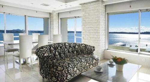 a living room with a couch and a table and windows at Hamanako Lake Side Plaza in Hamamatsu