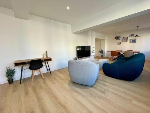 a living room with two blue chairs and a television at Le Design proche de la mer in Le Tréport